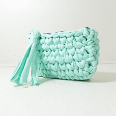 a crocheted purse with a tasseled handle and long strap, sitting on a white surface