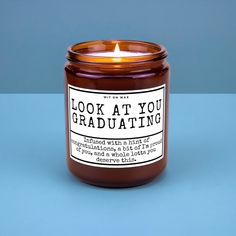 a candle that reads look at you graduating next to a blue background with the words looking at you on it