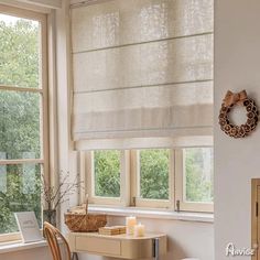 a room with two windows and a desk in front of the window is lit by candles