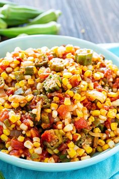 a bowl filled with corn and vegetables on top of a blue cloth next to green beans