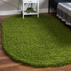 a green rug on the floor in a room with a bed and night stand next to it