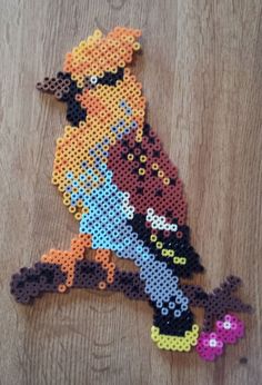 a cross stitch bird sitting on top of a wooden table