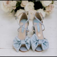 a pair of blue high heeled shoes sitting on top of a table next to flowers