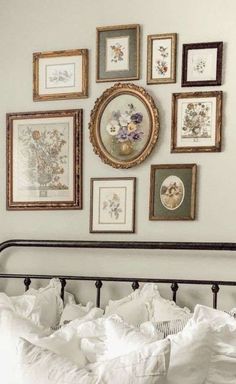 a bed with white linens and pictures on the wall above it in a bedroom