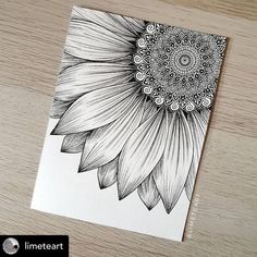 a black and white drawing of a sunflower on top of a wooden table next to a pen