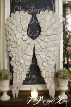 an angel wings decoration is on display in front of a chalkboard with christmas lights