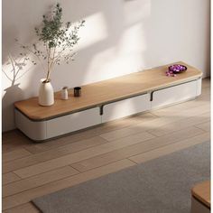 a living room with white walls and wooden flooring, two vases on top of the coffee table