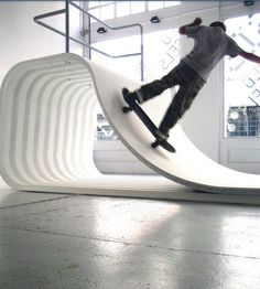 a man riding a skateboard on top of a wave shaped bench in a building