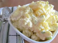 a white bowl filled with potato salad on top of a table