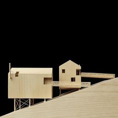 two wooden houses on top of a hill next to a black background and one is made out of wood