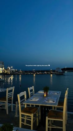 an outdoor dining area with tables and chairs overlooking the water at night, lit up by street lights