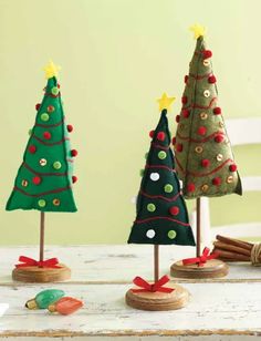 three small christmas trees sitting on top of a table next to cinnamon sticks and other decorations