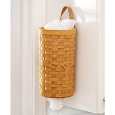 a laundry basket hanging on the wall next to a toilet paper dispenser