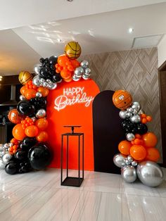 an orange and black birthday decoration with basketballs, balloons and streamers on the floor