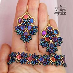 a hand holding two pairs of colorful earrings