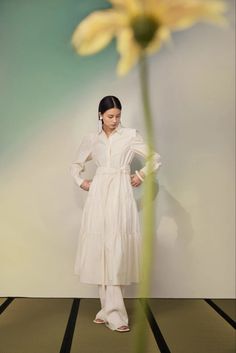 a woman standing next to a yellow flower