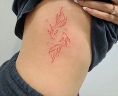 a woman with a tattoo on her back shows the outline of a goldfish in red ink