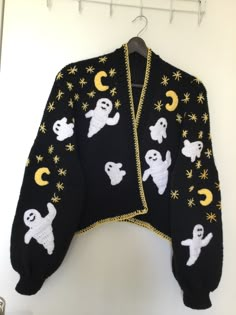 a black sweater with white ghost and stars on it hanging from a coat hanger