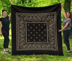 two women holding up a black and white quilt