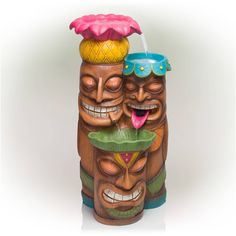 two tiki statues with one drinking from a water faucet and the other wearing goggles