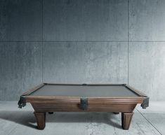 a pool table sitting on top of a wooden floor next to a wall with a gray background