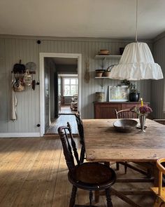 a wooden table sitting in the middle of a kitchen next to a light hanging above it