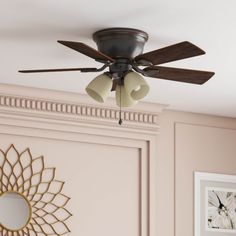 a ceiling fan mounted on the side of a wall in a room with pink walls