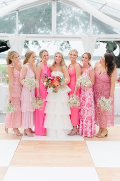 a group of women standing next to each other in front of a white and pink tent