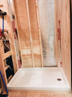 the shower is being installed in the bathroom with wood walls and flooring around it