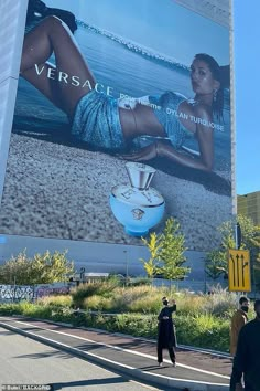 a large advertisement on the side of a building in front of a woman's body