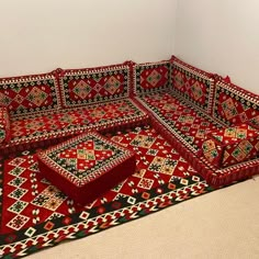 a red couch sitting on top of a carpet covered floor next to a white wall