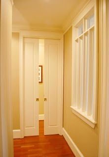 an empty hallway with wooden floors and white trim on the doors, windows, and window sill