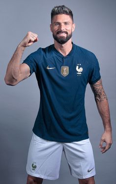 a man posing for a photo with his arm raised in the air while wearing a blue shirt and white shorts