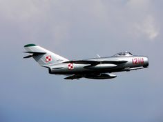 a fighter jet flying in the sky on a cloudy day with red and white markings