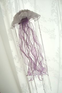 a purple jellyfish floating in the air on top of a white sheeted wall