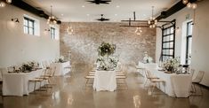 a room filled with lots of tables covered in white linens and topped with flowers