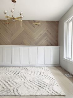 an empty room with wood paneling and chandelier hanging from the ceiling, along with a rug on the floor