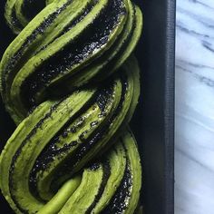 a box filled with green and black donuts on top of a marble countertop