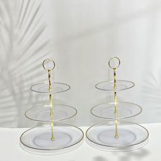 three clear plates with gold handles on each one are stacked in the shape of circles