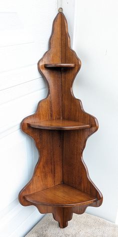 a three tiered wooden shelf on the side of a wall next to a door