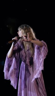 a woman in a purple dress holding a microphone