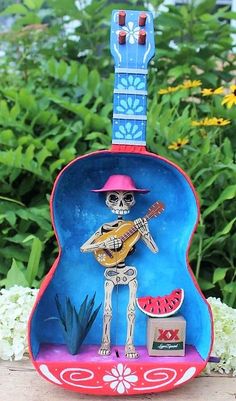 a guitar shaped like a skeleton with a hat and watermelon on its neck