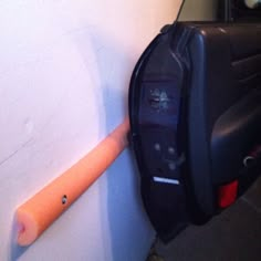 a black piece of luggage sitting next to a white wall