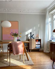 a dining room with a table, chairs and a vase filled with flowers on top of it