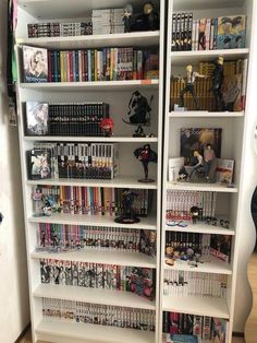 a white bookcase filled with lots of books and video game memorabilia on top of it