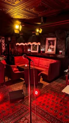 a room with red couches, chairs and a microphone in the middle of it