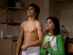 the young man and woman are standing next to each other in front of some shelves