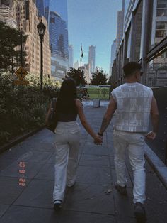 two people walking down a sidewalk holding hands