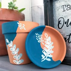 two plant pots sitting next to each other on a shelf