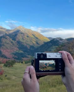 someone holding up a camera in front of mountains